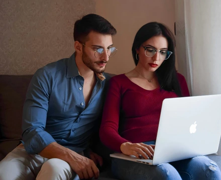 A couple (man and woman) using a laptop to research online therapy provider options.