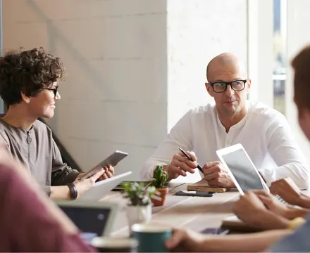 Group of people sitting at a table with their laptops open discussing their therapy options.