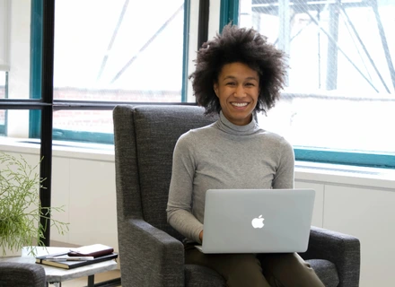 A woman sitting on a chair with her laptop open looking for their therapist options.