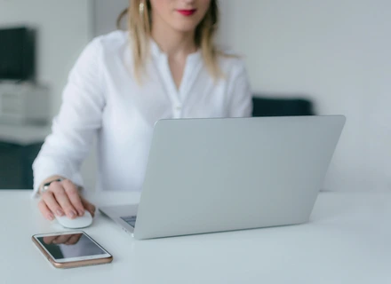 A woman sitting at a desk with her laptop open looking for their therapist options.