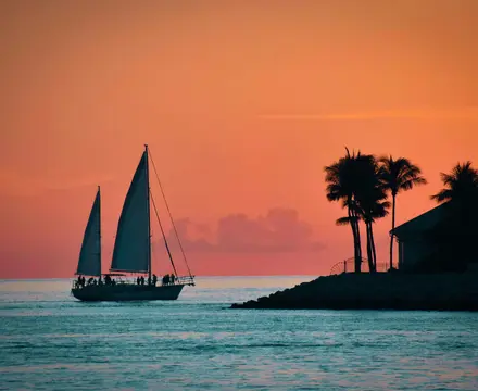 Cinematic shot of sailboat on the water off Florida Key West with a sunset in the background.