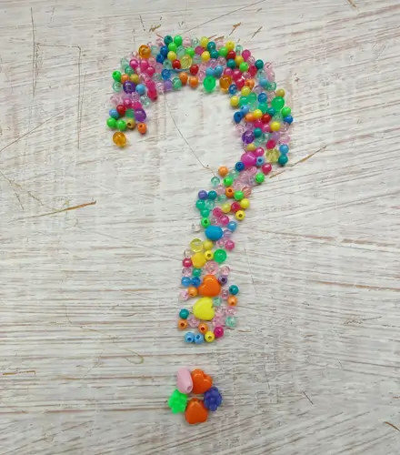 A question mark symbol on the table made out of colorful beads.