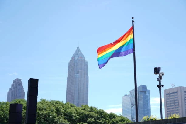 Ohio skyline with a LGBTQIA+ flag flying in the wind and a blue sky in the background.