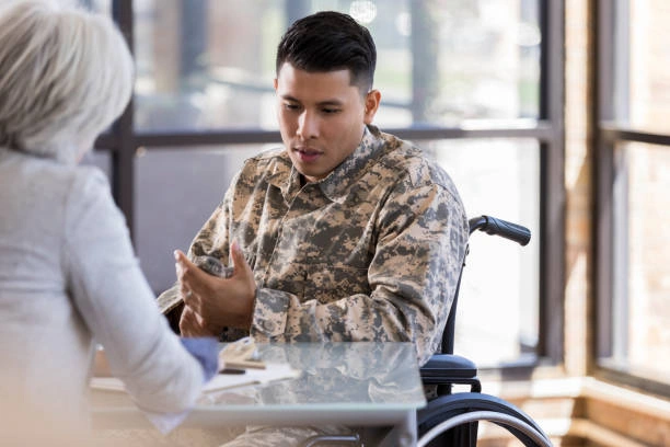 A military solider in uniform in a wheelchair talking with his medical provider.
