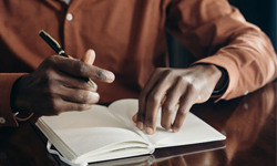 Man using a note book and taking notes while on a video call