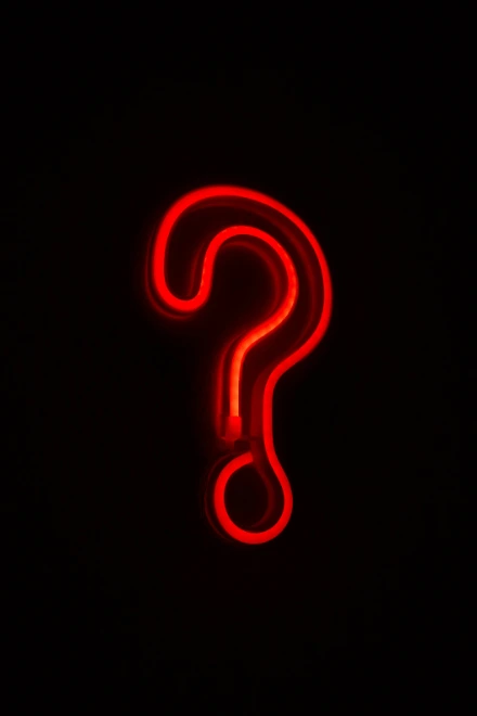 Bright red neon question mark glowing against black background, representing questions about insomnia therapy and sleep treatment