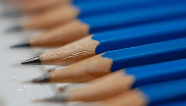 Row of identical blue pencils perfectly aligned in precise order, representing the need for symmetry, order, and repetitive patterns characteristic of OCD behaviors
