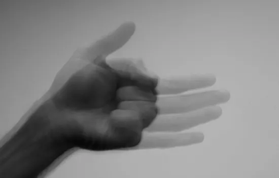 Blurred black and white image of an outstretched hand appearing to shake or tremble, illustrating the physical symptoms experienced during panic attacks