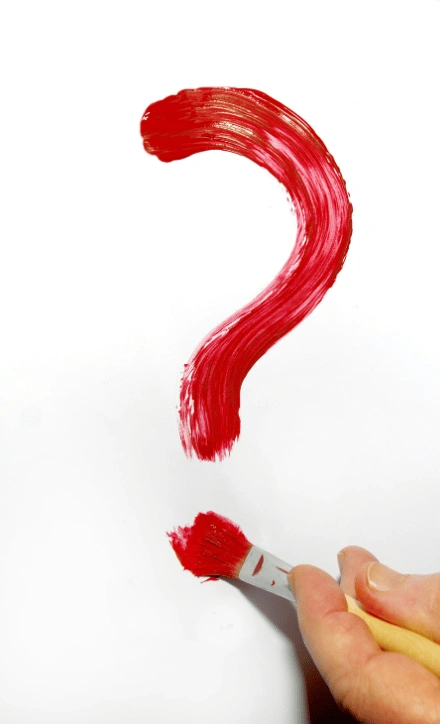 Hand holding paintbrush creating large red question mark on white canvas, representing questions about social anxiety therapy and seeking help