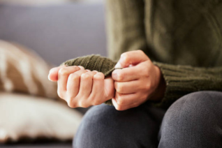 Close-up of hands clasped together tightly in lap, showing tension and anxiety as someone attempts to self-soothe during panic or anxiety episodes